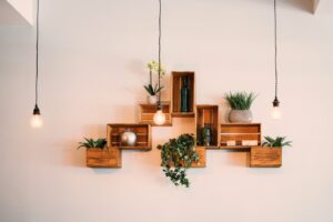 Contemporary wooden shelves with plants and decor, illuminated by hanging lights.