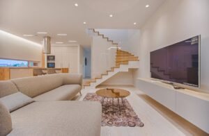 Spacious modern living room featuring stairs, a TV, and sleek furniture design.