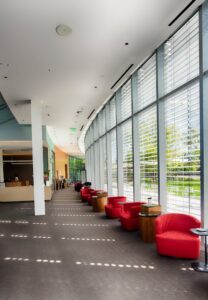 Spacious contemporary lobby with red lounge chairs and expansive windows for natural light.