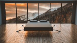 Minimalist bedroom with large windows offering a breathtaking mountain view during sunset.